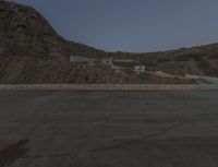 a lone motorcycle in the middle of the desert at dusk, with a building in the back ground