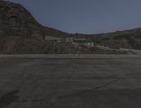 a lone motorcycle in the middle of the desert at dusk, with a building in the back ground