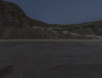 a lone motorcycle in the middle of the desert at dusk, with a building in the back ground