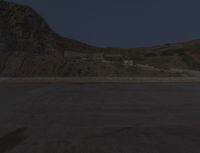 a lone motorcycle in the middle of the desert at dusk, with a building in the back ground