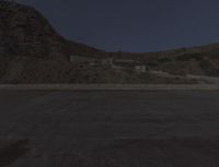 a lone motorcycle in the middle of the desert at dusk, with a building in the back ground