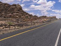 the empty street is on the rocky hill side and yellow paint shows the line of a curving road