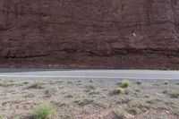 a person riding a motorcycle along a narrow road through rocks and sand cliffs a grassy area on both sides