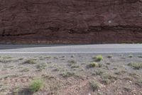 a person riding a motorcycle along a narrow road through rocks and sand cliffs a grassy area on both sides