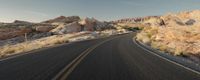 a winding road through the desert with rocky formations on both sides of the road and no traffic