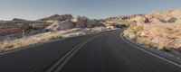 a winding road through the desert with rocky formations on both sides of the road and no traffic