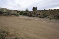 a desert road through the hills with some rocks and bushes on either side of the path