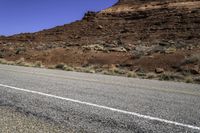 a stop sign is placed near the side of a desert road with no traffic or any cars to the left