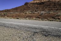 a stop sign is placed near the side of a desert road with no traffic or any cars to the left