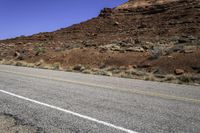 a stop sign is placed near the side of a desert road with no traffic or any cars to the left