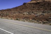 a stop sign is placed near the side of a desert road with no traffic or any cars to the left