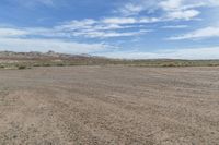 an empty field next to a big mountain with rocks in the background of the picture