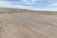 an empty field next to a big mountain with rocks in the background of the picture