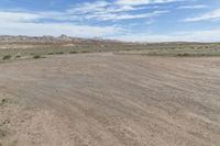 an empty field next to a big mountain with rocks in the background of the picture