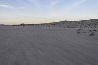 a car parked on the side of the road by the mountains in the desert, near a man