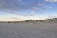 a car parked on the side of the road by the mountains in the desert, near a man