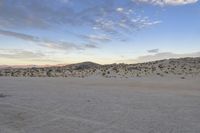 a car parked on the side of the road by the mountains in the desert, near a man