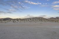 a car parked on the side of the road by the mountains in the desert, near a man