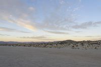 a car parked on the side of the road by the mountains in the desert, near a man