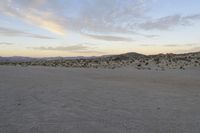 a car parked on the side of the road by the mountains in the desert, near a man
