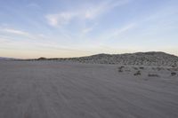 a car parked on the side of the road by the mountains in the desert, near a man