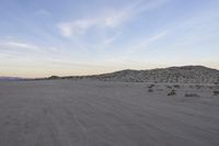 a car parked on the side of the road by the mountains in the desert, near a man