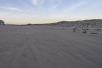 a car parked on the side of the road by the mountains in the desert, near a man
