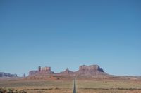 a desert road that leads out to the mountains in distance with a truck going under it
