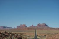 a desert road that leads out to the mountains in distance with a truck going under it