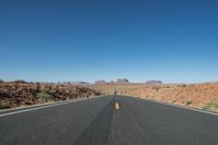a desert road that leads out to the mountains in distance with a truck going under it