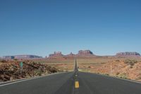a desert road that leads out to the mountains in distance with a truck going under it