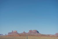 a desert road that leads out to the mountains in distance with a truck going under it