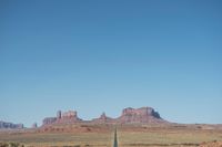 a desert road that leads out to the mountains in distance with a truck going under it