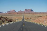 a desert road that leads out to the mountains in distance with a truck going under it