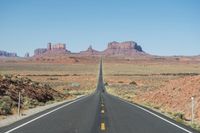 a desert road that leads out to the mountains in distance with a truck going under it