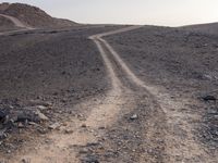 a truck on a dirt road in the desert with rocks and stones on the ground