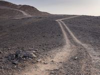 a truck on a dirt road in the desert with rocks and stones on the ground