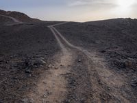 a truck on a dirt road in the desert with rocks and stones on the ground