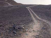 a truck on a dirt road in the desert with rocks and stones on the ground