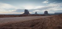 a dirt road is in the middle of the desert with rocks and rock formations in the distance