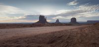 a dirt road is in the middle of the desert with rocks and rock formations in the distance