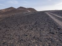 a truck on a dirt road in the desert with rocks and stones on the ground