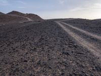 a truck on a dirt road in the desert with rocks and stones on the ground