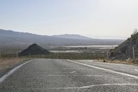 a motorcycle riding down a winding highway between hills and dry grass on a sunny day