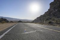 a motorcycle riding down a winding highway between hills and dry grass on a sunny day