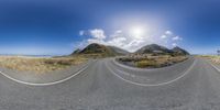 a wide angle fisheye lens picture of the road in the desert near mountains and beach