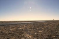 a lone airplane flying above the plain of an empty, dry area in the middle of a desert