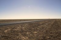 a lone airplane flying above the plain of an empty, dry area in the middle of a desert