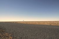 a lone airplane flying above the plain of an empty, dry area in the middle of a desert