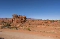 a dirt road with rocks on it near a rocky mountain range that looks like desert